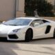 A white lamborghini moving in a driveway.